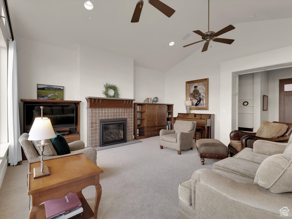 Carpeted living room featuring high vaulted ceiling, ceiling fan, and a tile fireplace