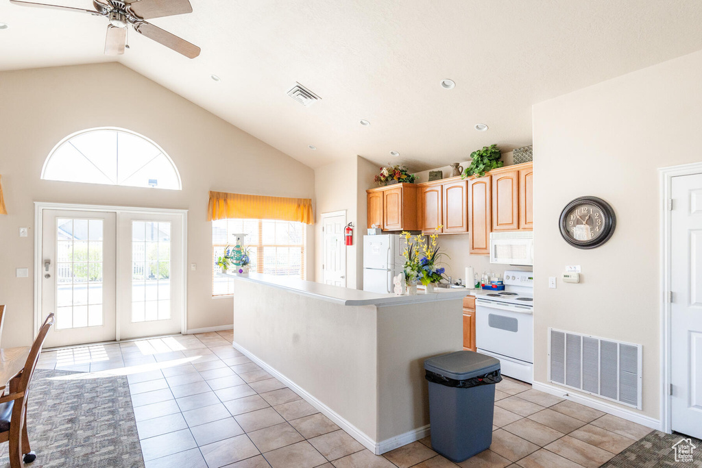 Kitchen featuring ceiling fan, light tile floors, a kitchen island, white appliances, and lofted ceiling