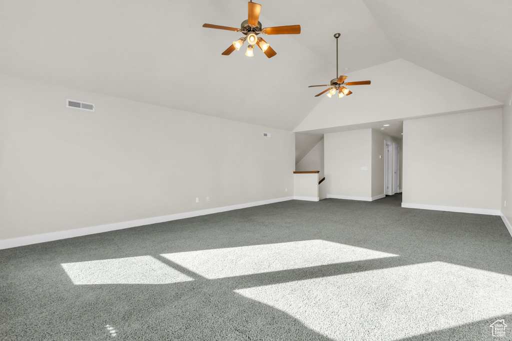 Interior space featuring high vaulted ceiling, dark colored carpet, and ceiling fan