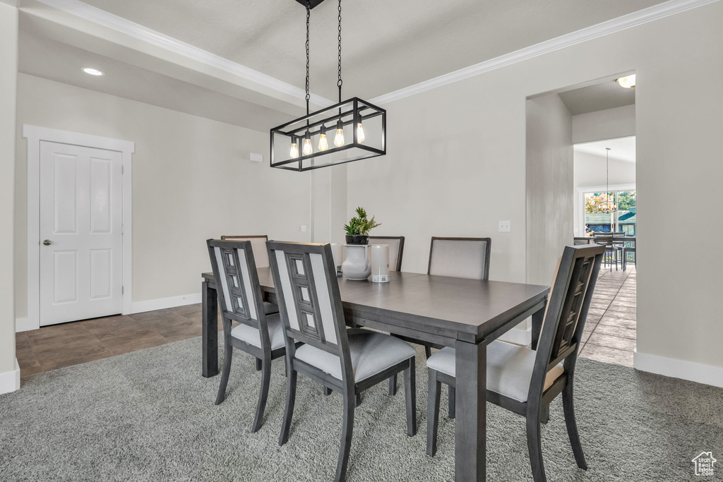 Dining space featuring a notable chandelier, dark tile flooring, and crown molding