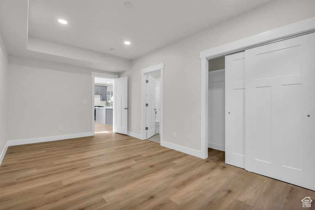 Unfurnished bedroom featuring a closet, ensuite bath, and light hardwood / wood-style floors