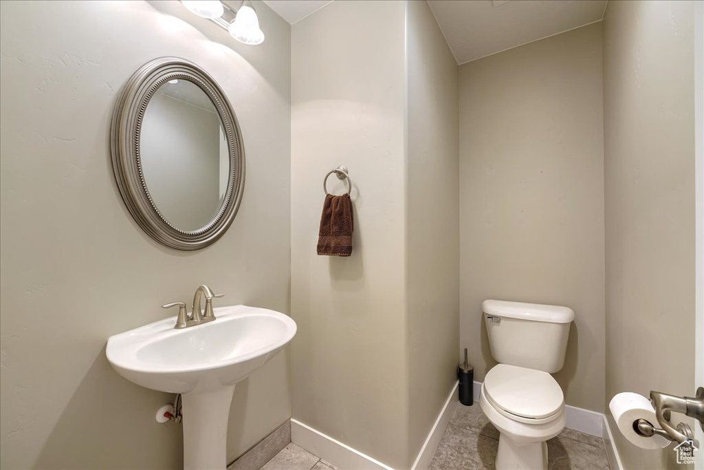 Bathroom featuring tile floors, lofted ceiling, and toilet