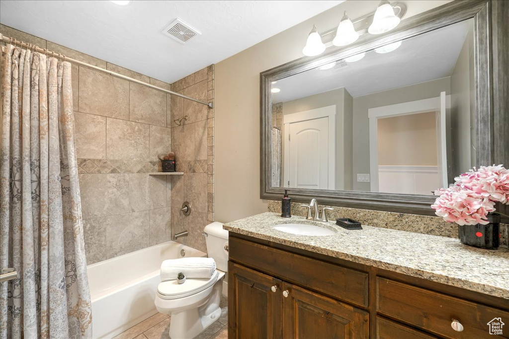 Full bathroom with tile flooring, oversized vanity, shower / tub combo, and toilet