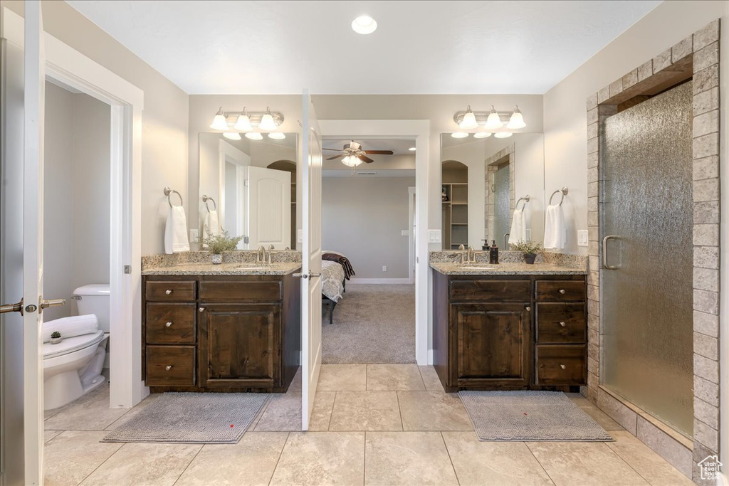 Bathroom with vanity with extensive cabinet space, ceiling fan, tile floors, and toilet
