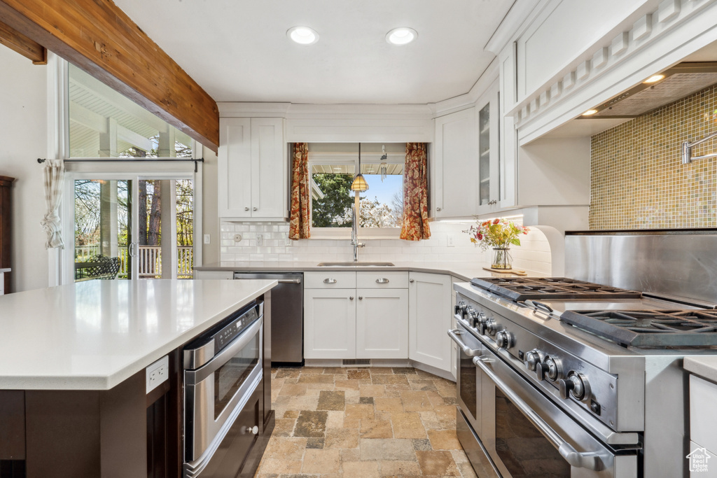 Kitchen featuring white cabinets, sink, light tile flooring, tasteful backsplash, and stainless steel appliances