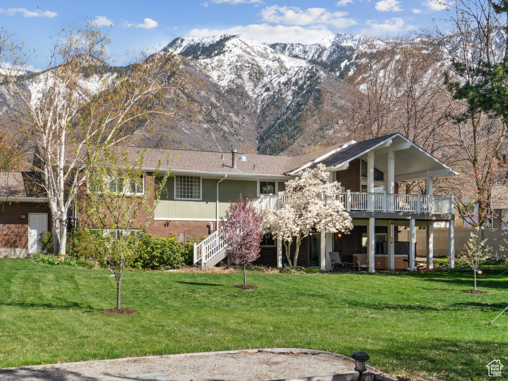 Rear view of house featuring a mountain view, a yard, and a balcony
