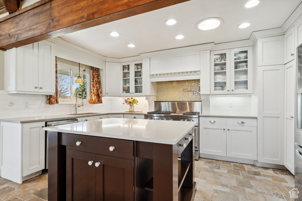 Kitchen with backsplash, sink, a kitchen island, and white cabinetry