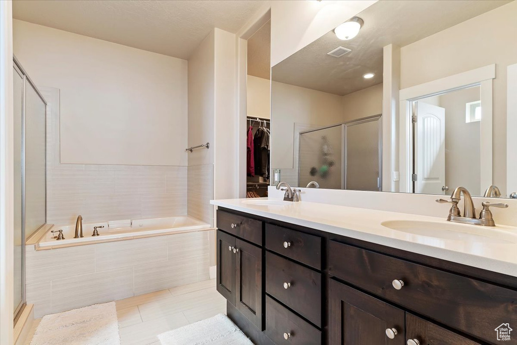 Bathroom featuring tile flooring, vanity with extensive cabinet space, double sink, and plus walk in shower