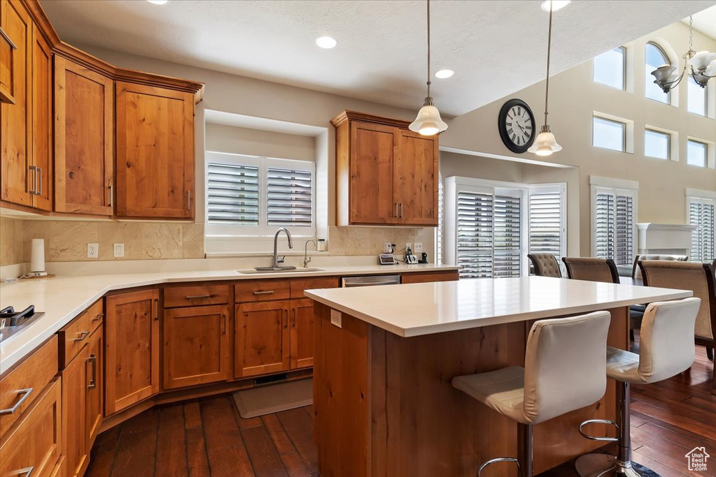 Kitchen with backsplash, pendant lighting, dark hardwood / wood-style floors, and a breakfast bar