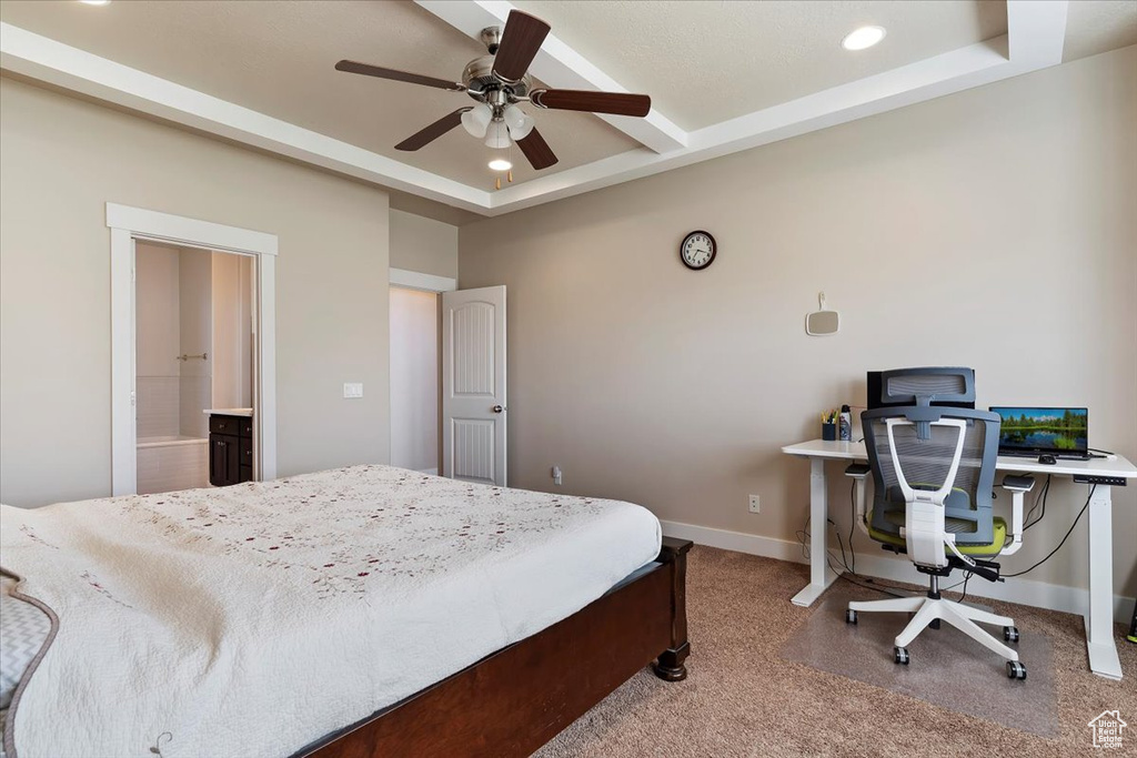 Bedroom with ensuite bath, a raised ceiling, ceiling fan, and carpet