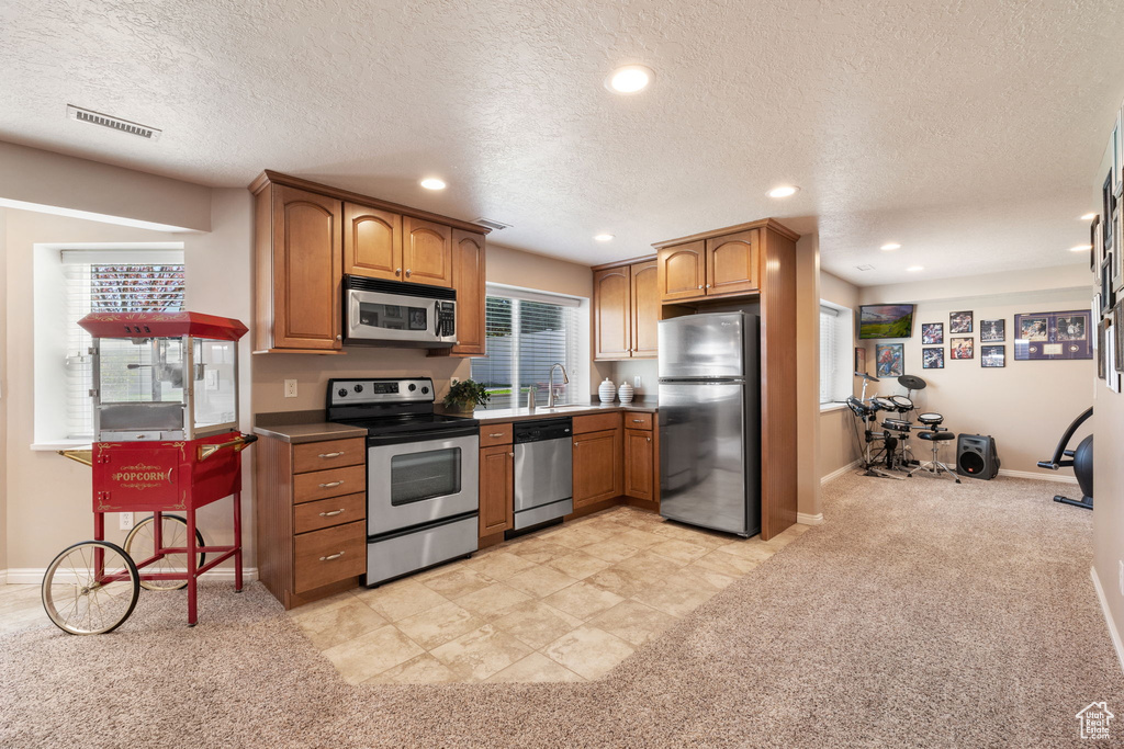Kitchen featuring a wealth of natural light, a textured ceiling, stainless steel appliances, and light tile floors