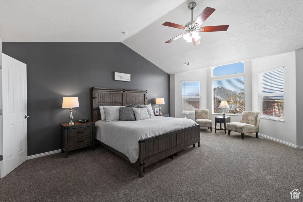 Bedroom with dark colored carpet, ceiling fan, and vaulted ceiling