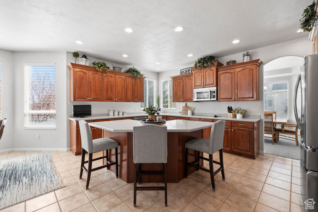 Kitchen featuring a kitchen island, a breakfast bar area, stainless steel appliances, and light colored carpet