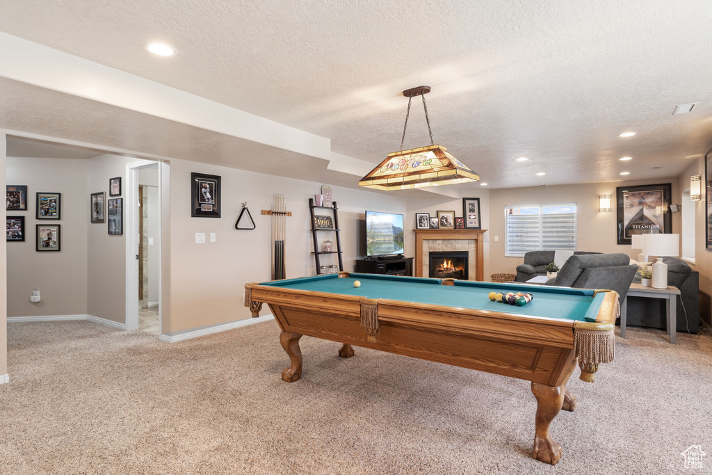 Playroom featuring light carpet, a tile fireplace, pool table, and a textured ceiling