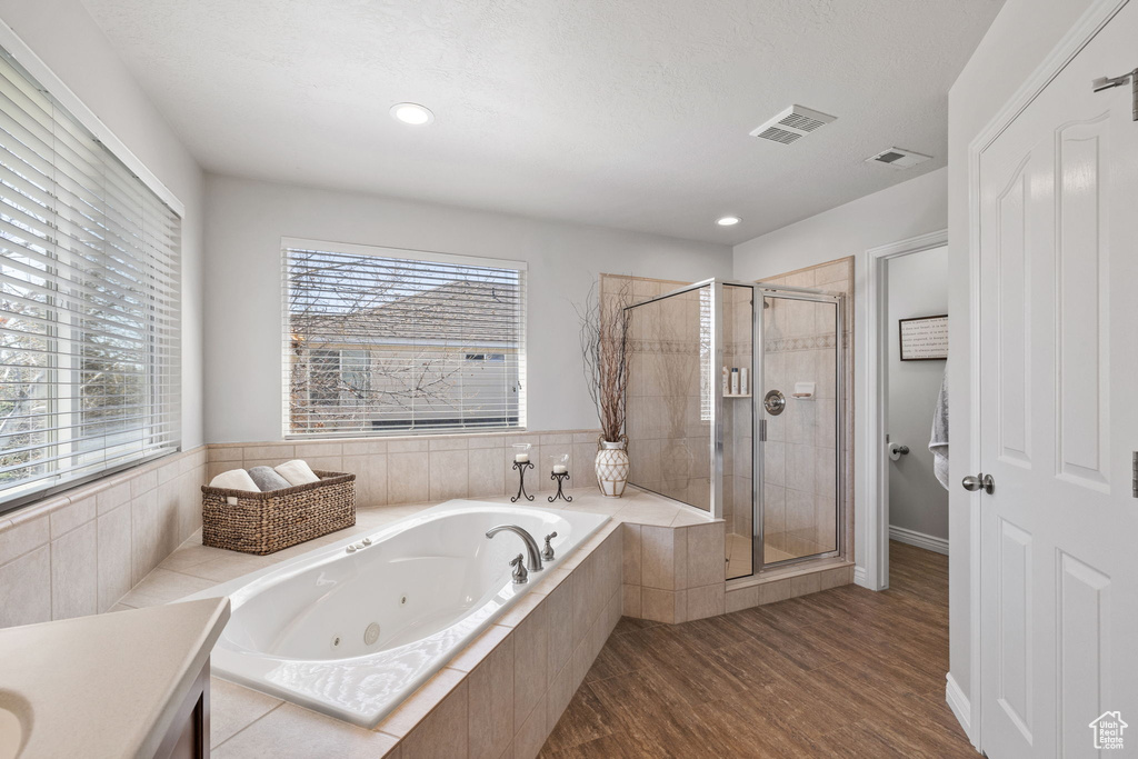 Bathroom featuring a wealth of natural light, hardwood / wood-style floors, and plus walk in shower