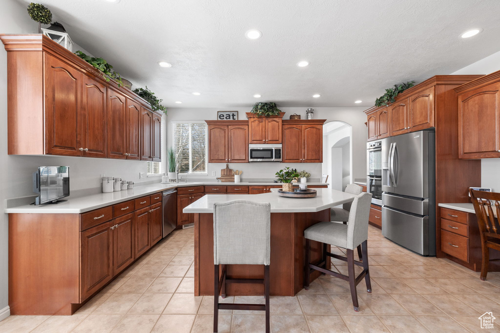 Kitchen featuring a kitchen island, stainless steel appliances, a breakfast bar, and light tile floors