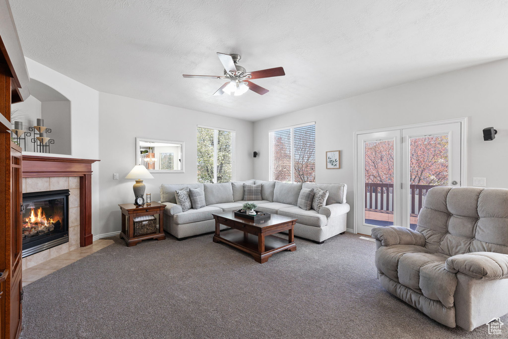 Carpeted living room with ceiling fan and a tile fireplace