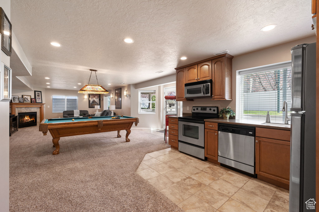 Kitchen with hanging light fixtures, billiards, stainless steel appliances, a wealth of natural light, and light tile floors