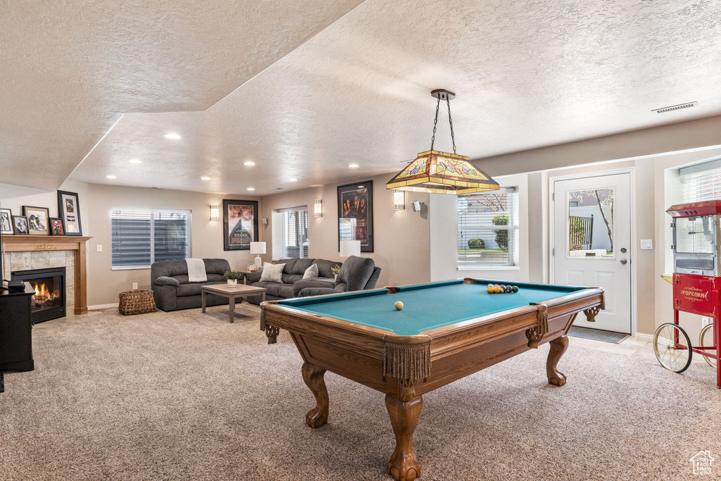 Recreation room featuring light colored carpet, a textured ceiling, billiards, and a tile fireplace