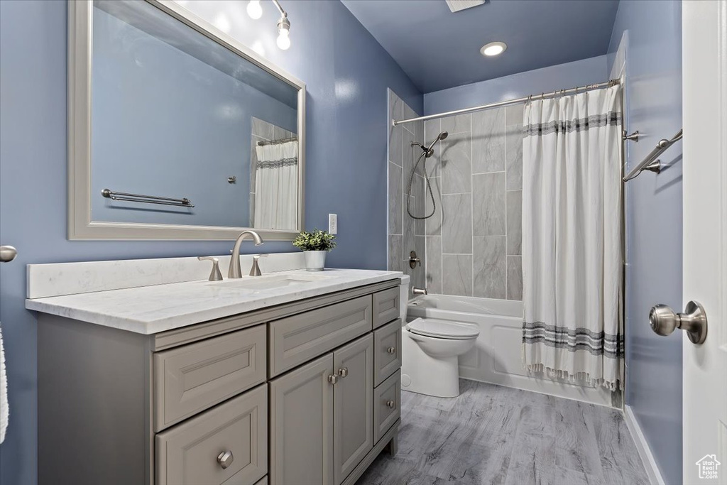 Full bathroom with hardwood / wood-style floors, shower / bath combo, toilet, and vanity with extensive cabinet space