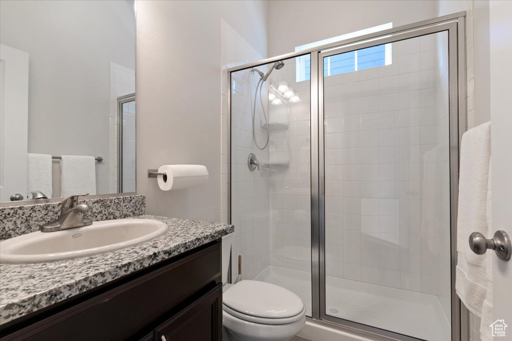 Bathroom with vanity with extensive cabinet space, an enclosed shower, and toilet