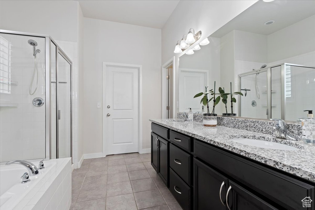 Bathroom with dual sinks, large vanity, tile floors, and plus walk in shower