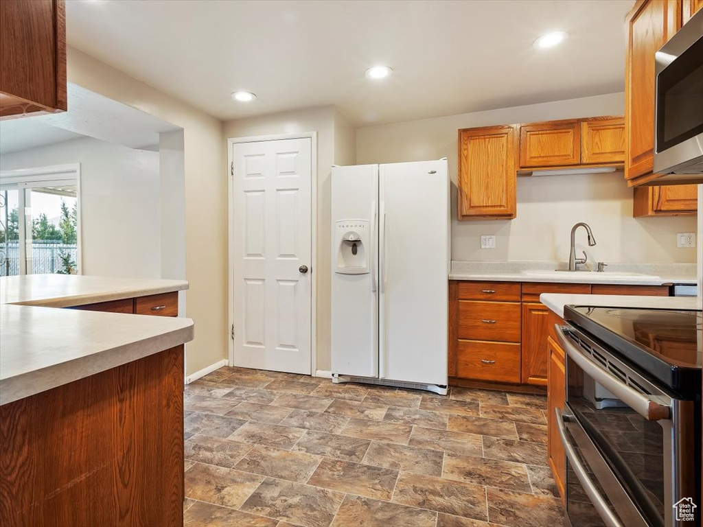 Kitchen featuring tile flooring, white fridge with ice dispenser, sink, and range