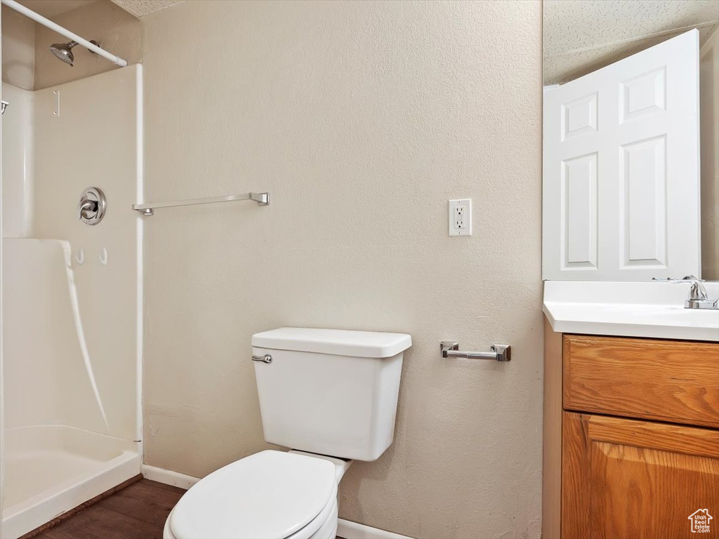 Bathroom featuring a shower, vanity, hardwood / wood-style flooring, and toilet