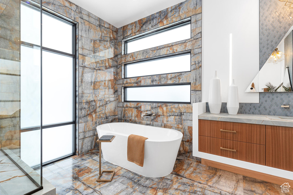 Bathroom with backsplash, vanity, tile walls, and tile flooring