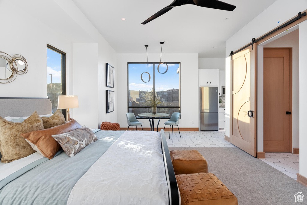 Bedroom with light carpet, multiple windows, stainless steel fridge, and a barn door