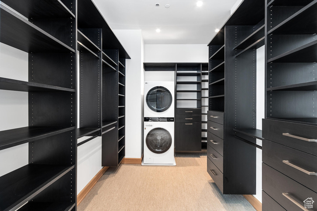 Spacious closet with light carpet and stacked washer and clothes dryer