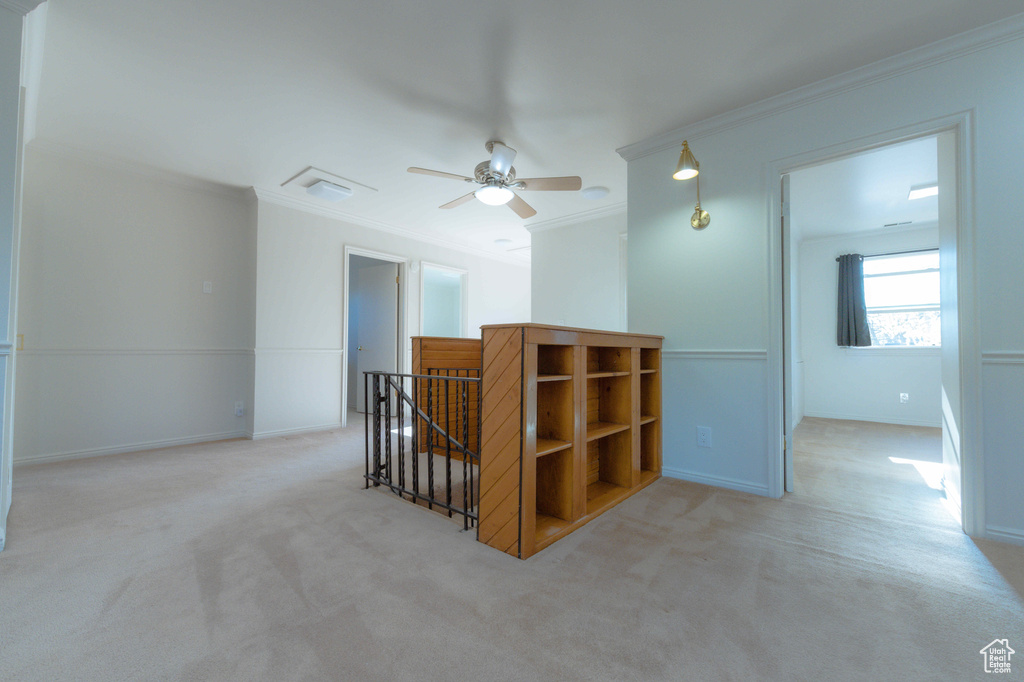 Spare room featuring ceiling fan, light carpet, and ornamental molding