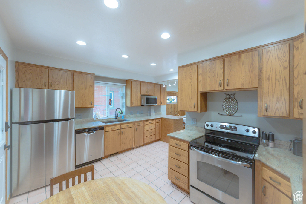 Kitchen featuring appliances with stainless steel finishes, light brown cabinets, sink, and light tile floors