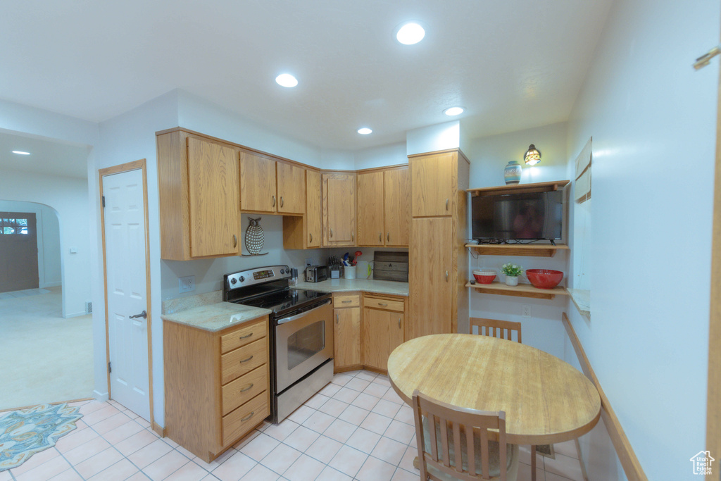 Kitchen with light brown cabinets, light tile floors, and stainless steel electric range oven