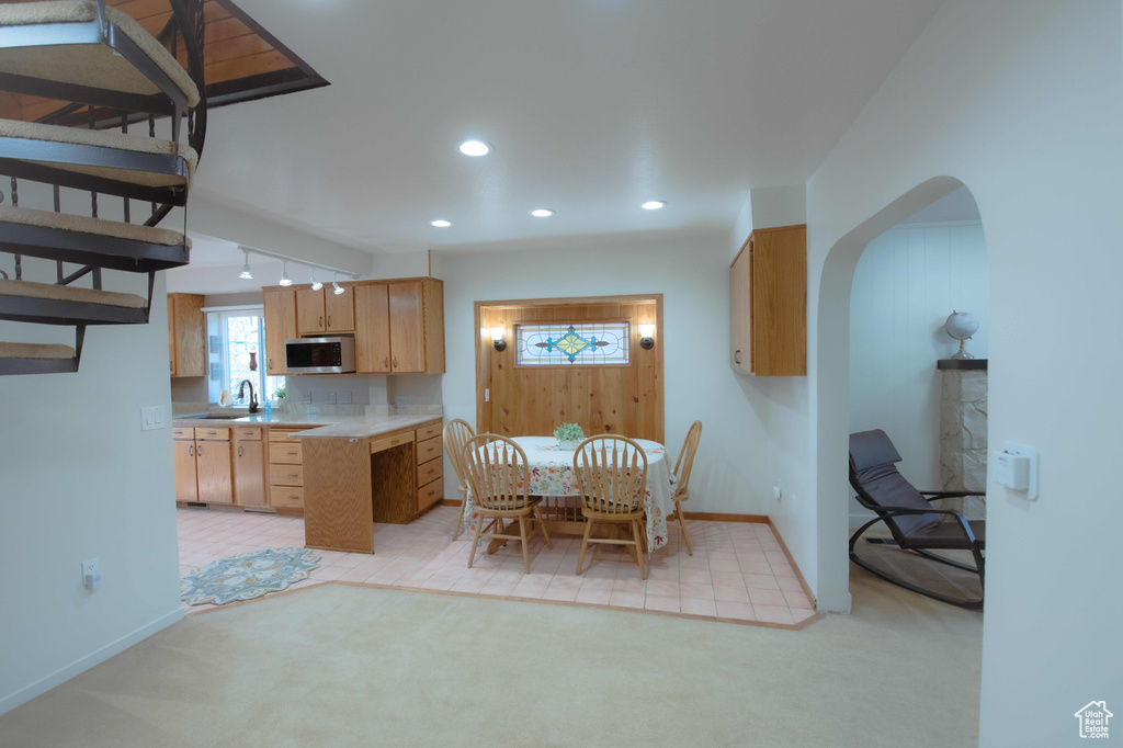 Unfurnished dining area featuring light colored carpet, sink, and rail lighting