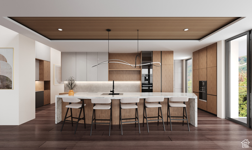 Kitchen with hanging light fixtures, dark hardwood / wood-style flooring, and a kitchen bar