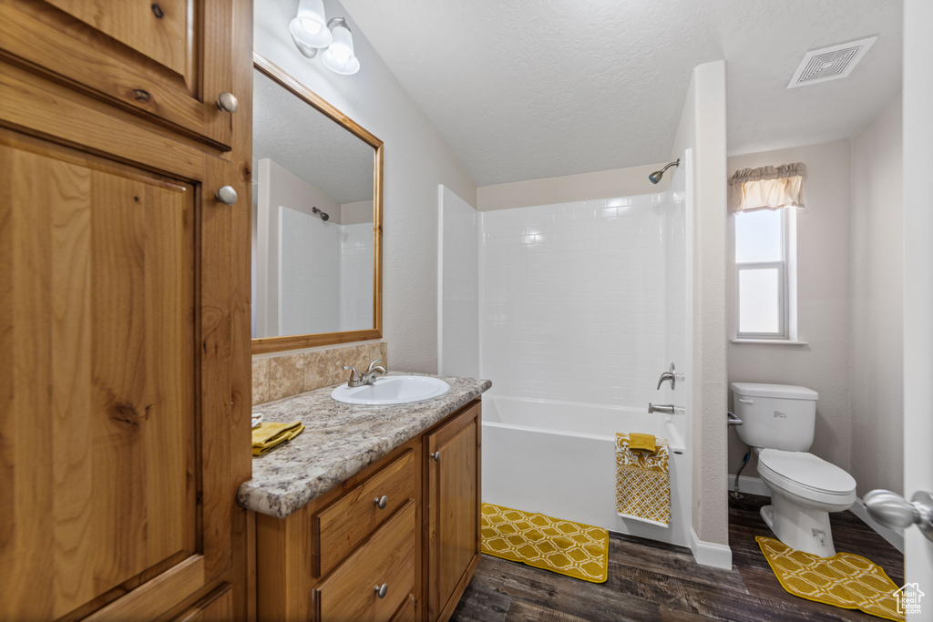 Full bathroom featuring hardwood / wood-style floors, vanity, toilet, and shower / tub combination