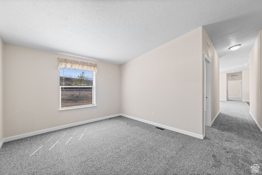 Spare room with a textured ceiling and dark carpet
