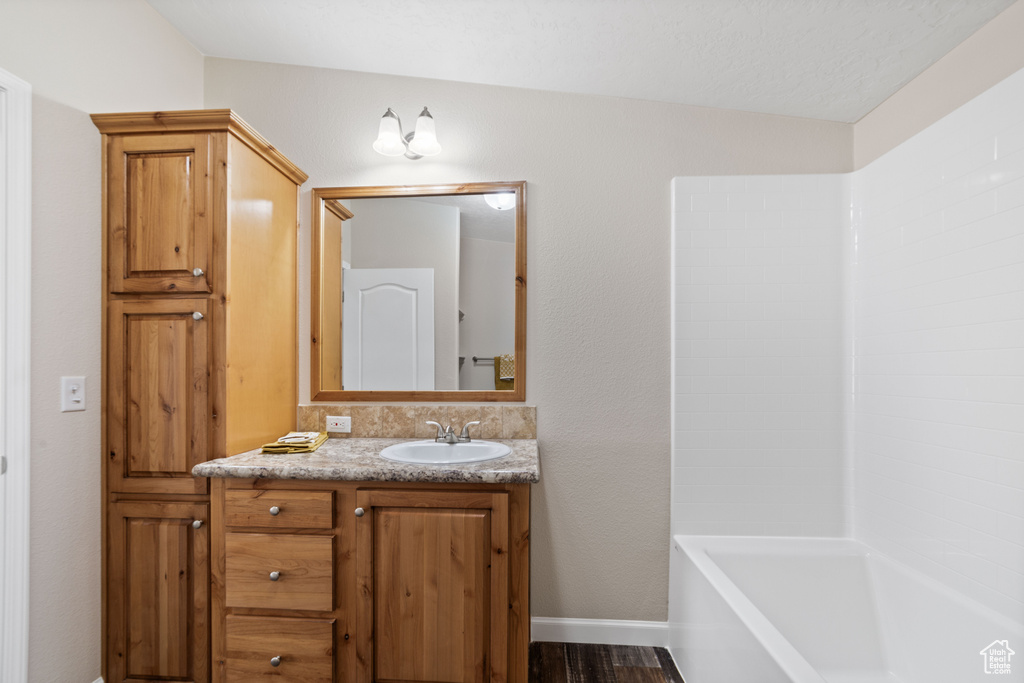 Bathroom featuring lofted ceiling, vanity, bathing tub / shower combination, and hardwood / wood-style flooring