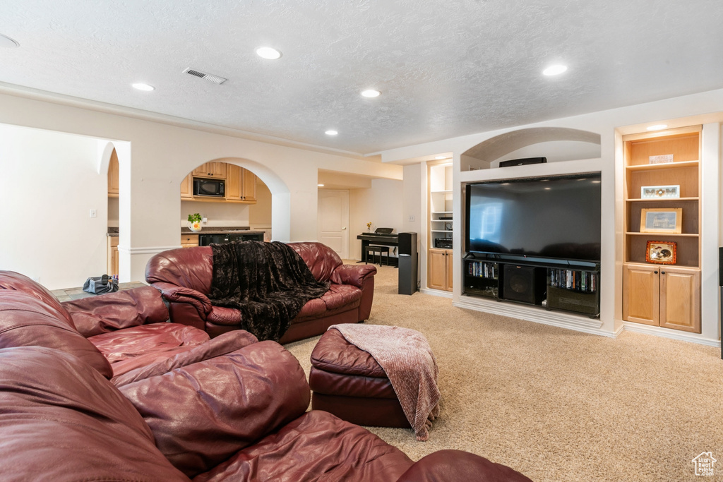 Living room featuring built in features, light colored carpet, and a textured ceiling