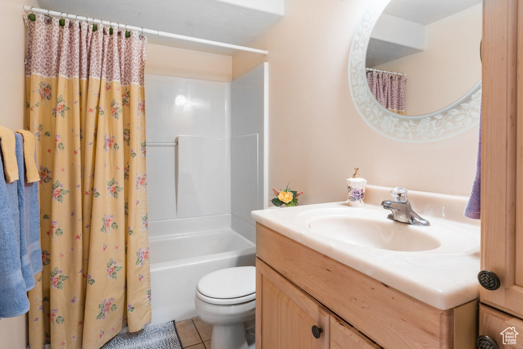 Full bathroom featuring toilet, tile flooring, shower / tub combo with curtain, and large vanity