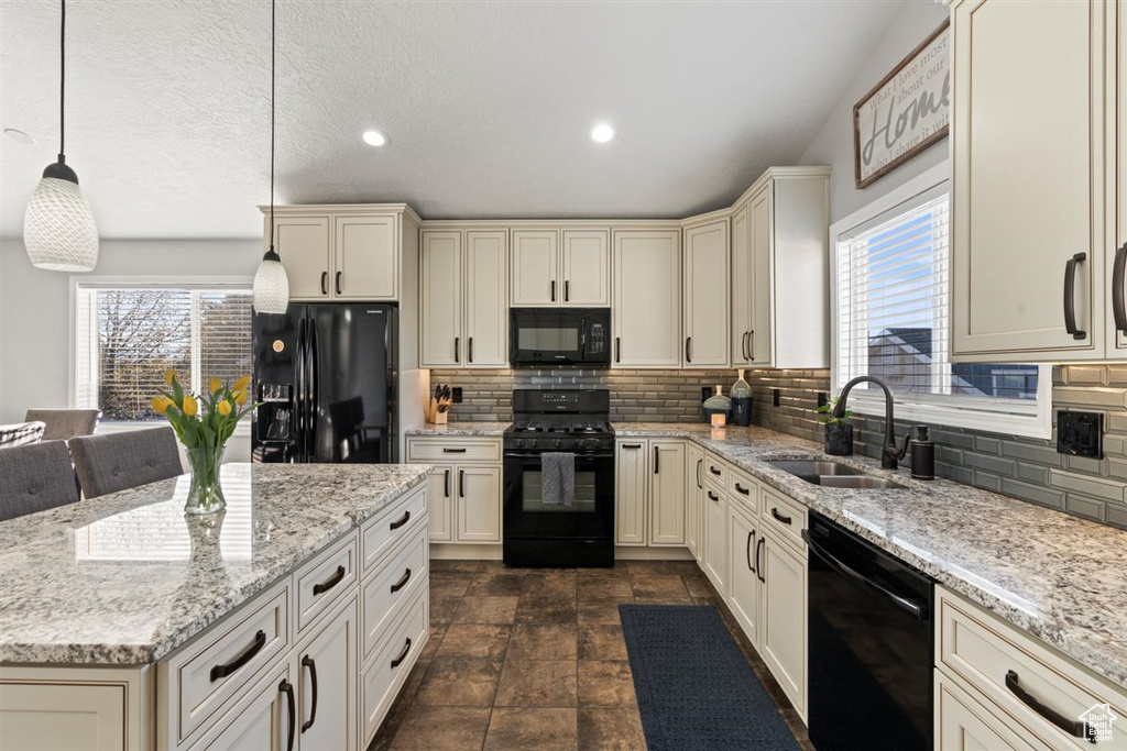 Kitchen featuring hanging light fixtures, plenty of natural light, sink, and black appliances