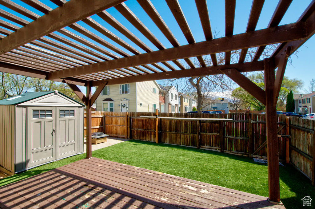 Wooden terrace with a lawn, a shed, and a pergola