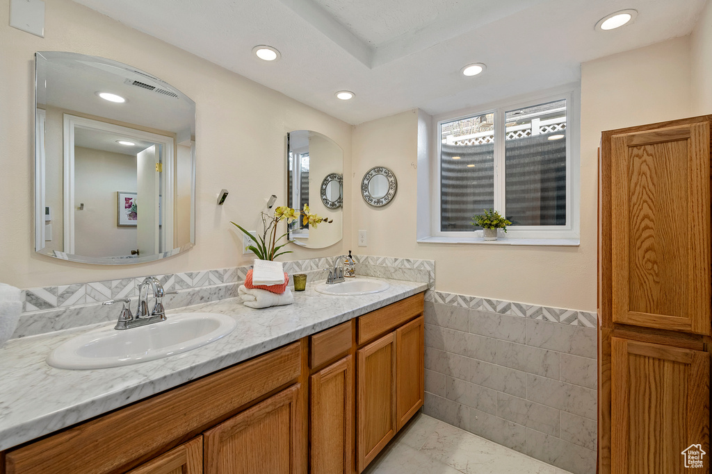 Bathroom featuring tile walls, tile flooring, and double sink vanity