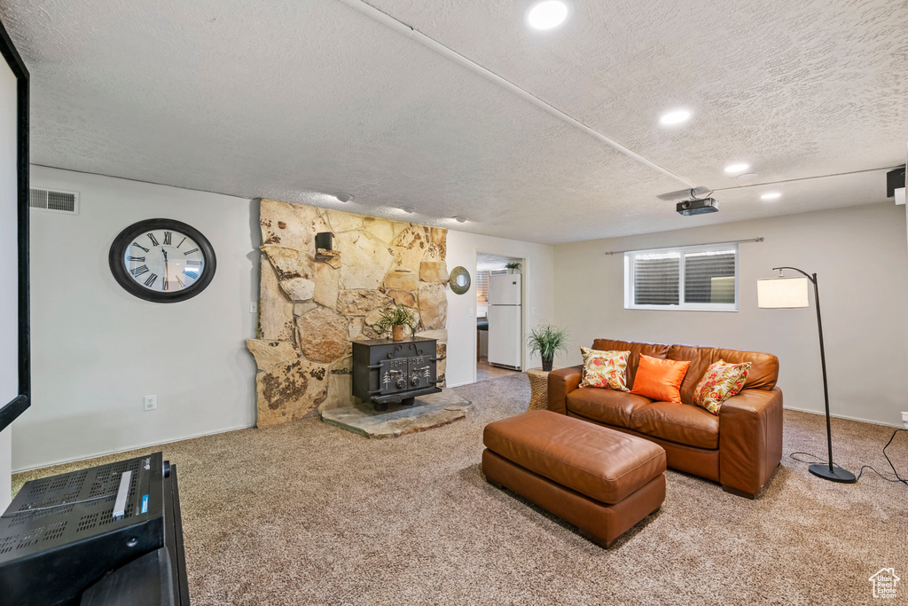 Carpeted living room with a textured ceiling and a wood stove