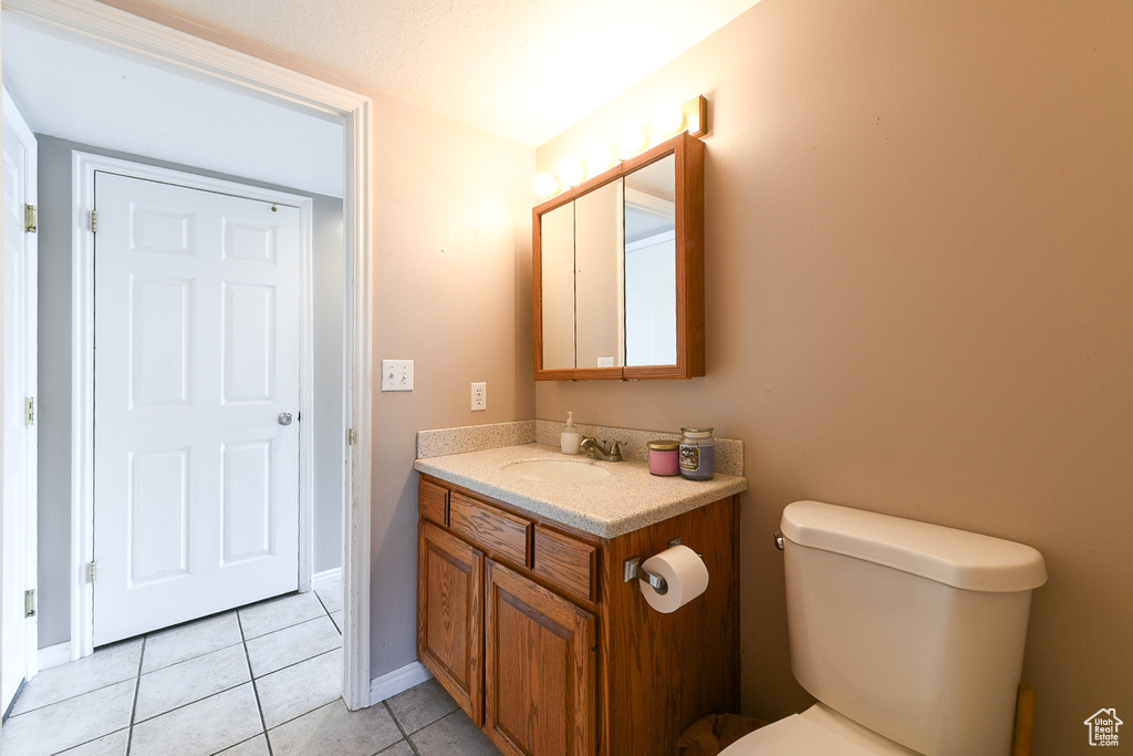 Bathroom featuring tile flooring, vanity with extensive cabinet space, and toilet