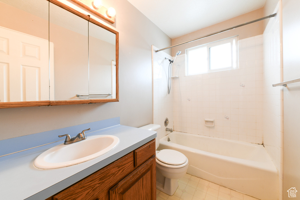 Full bathroom with tile flooring, oversized vanity, tiled shower / bath, and toilet