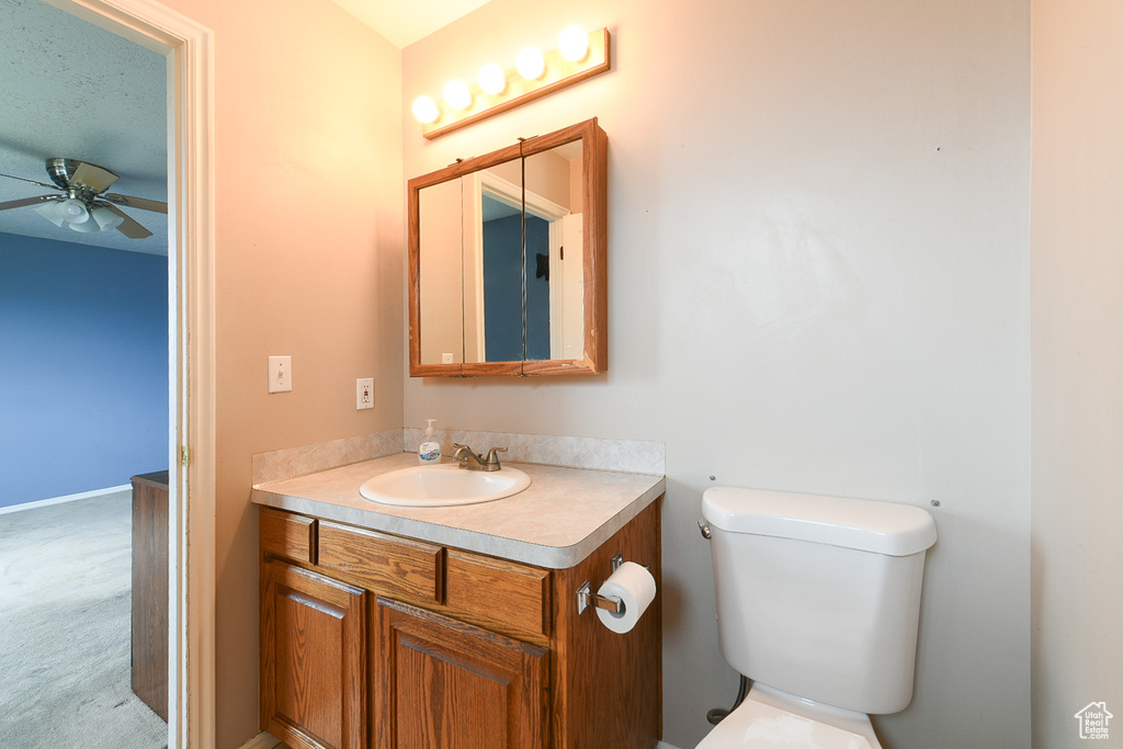 Bathroom with ceiling fan, vanity, and toilet