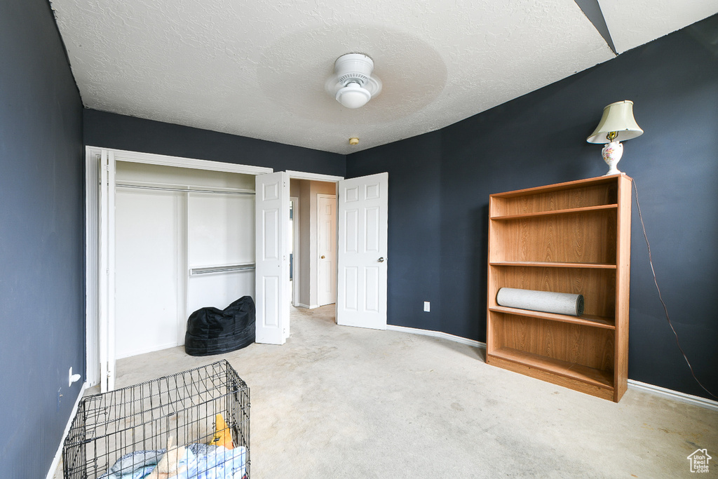 Bedroom featuring light carpet, a closet, ceiling fan, and a textured ceiling