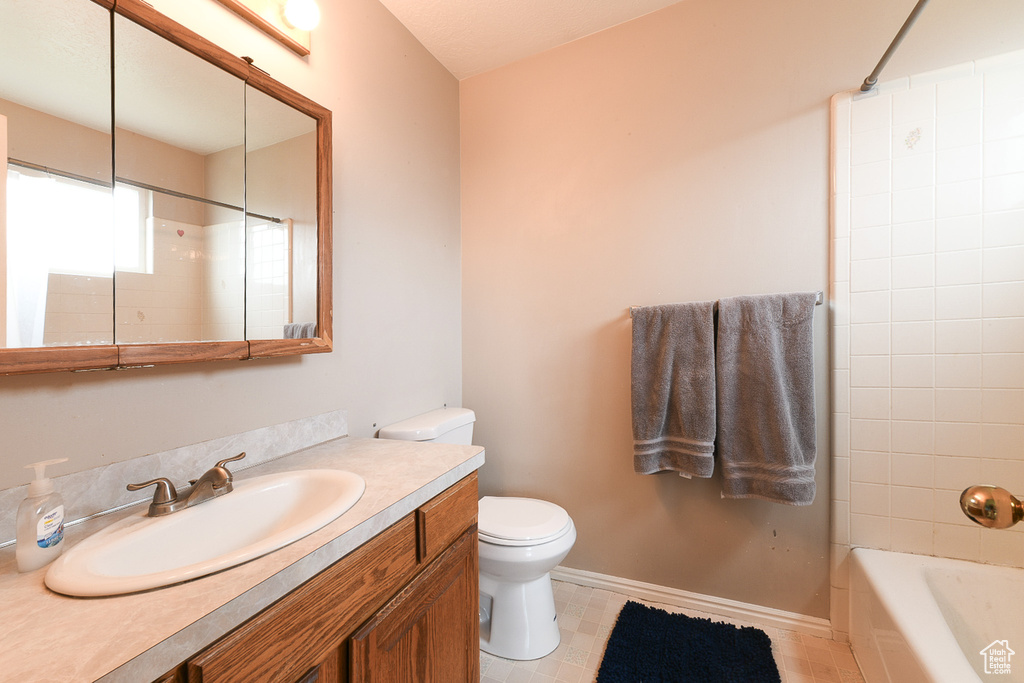 Full bathroom with tile floors, tiled shower / bath, toilet, and large vanity